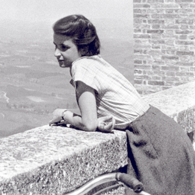 Foto von Rosalind Franklin, die sich auf eine Mauer stützt und in die Ferne blickt